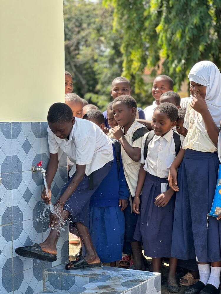 Kinder nutzen den neuen Brunnen in Afrika